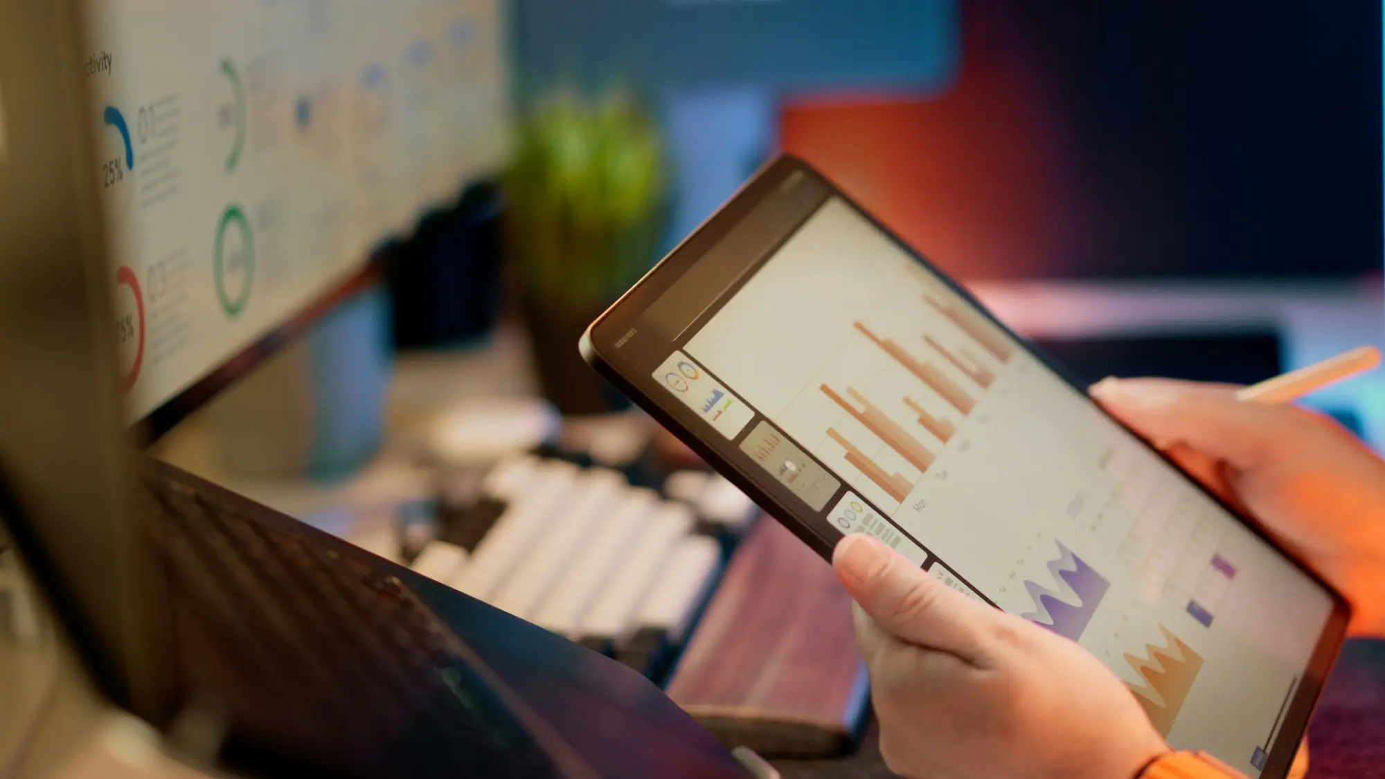 Bookkeeper or accountant at a desk with two monitors showing spreadsheets and reports