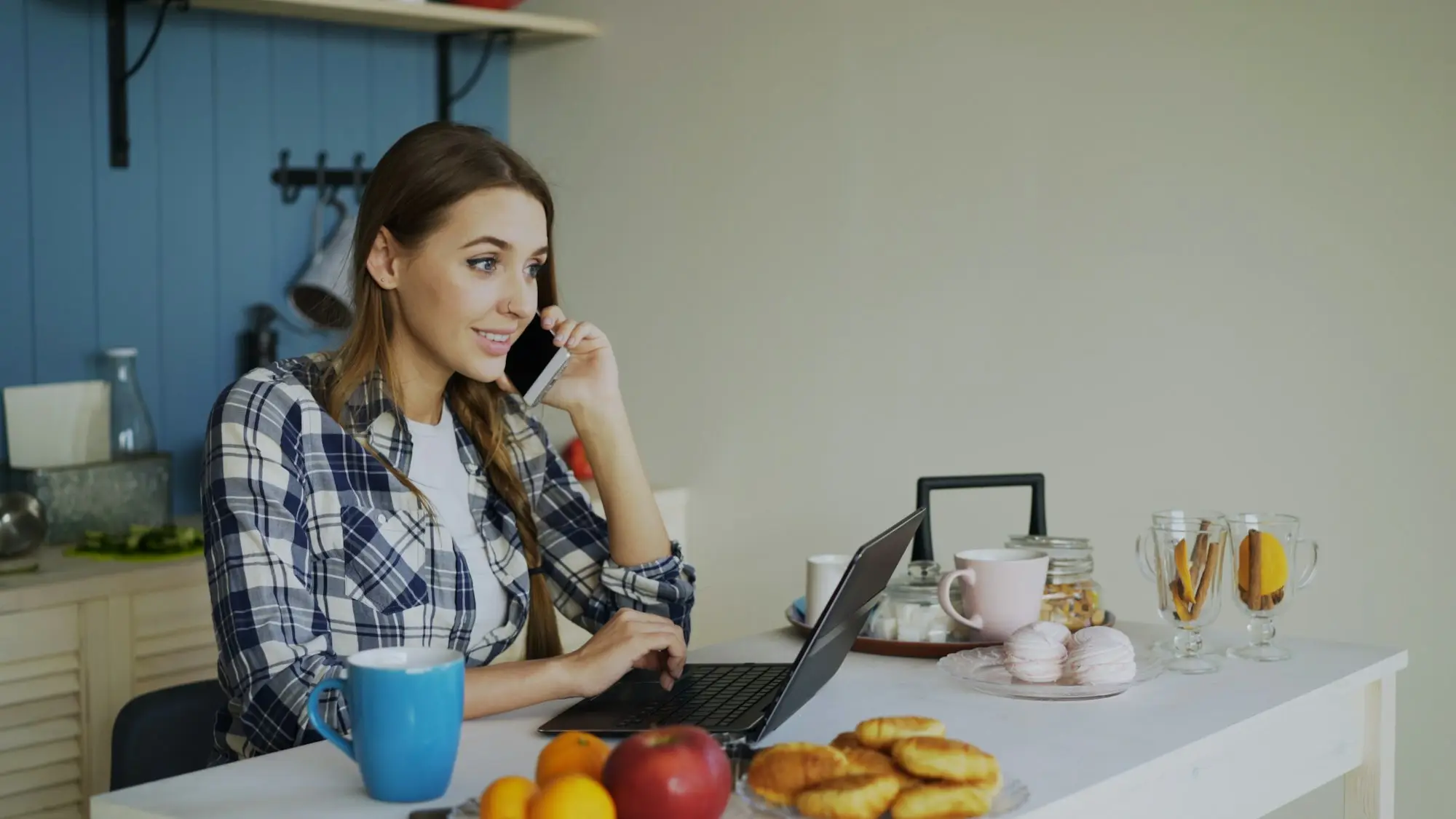 Small business founder at home kitchen table with laptop and notebook