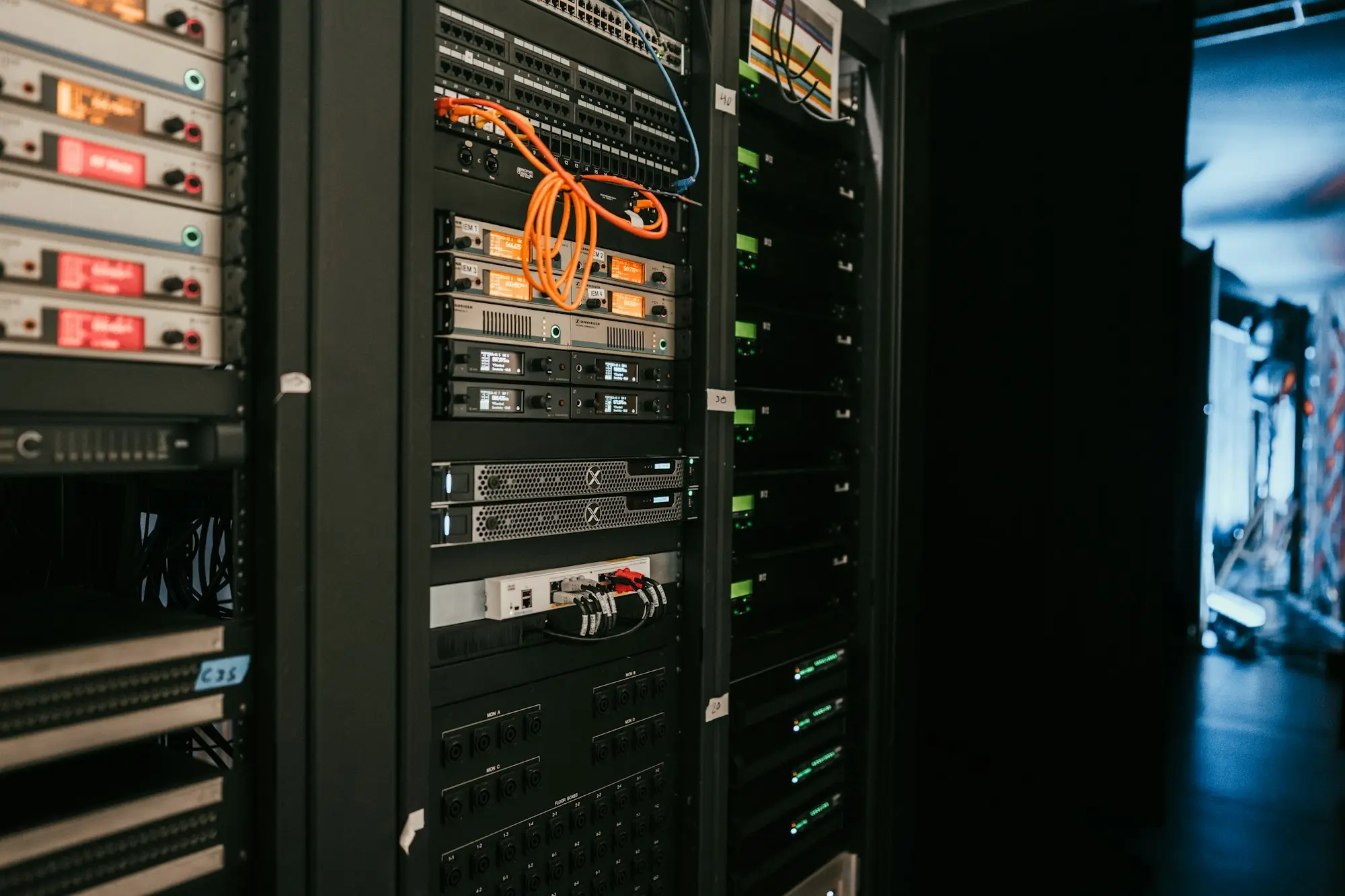 IT technician in a small server room checking network cables and a rack