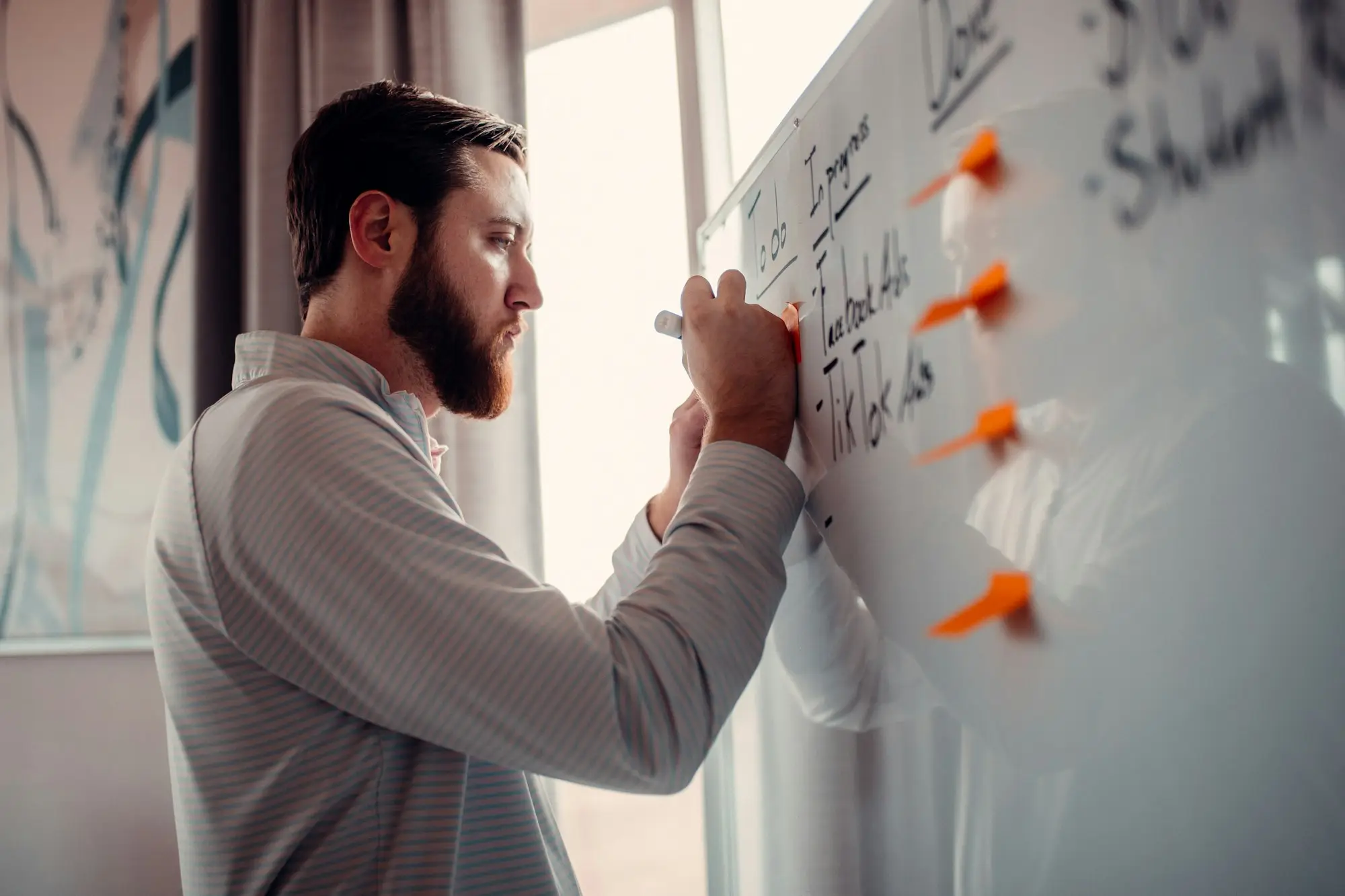 Two or three people in front of a whiteboard with a simple timeline/calendar plan in a small office